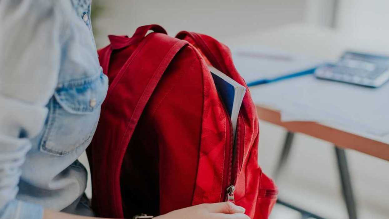 Student looking for something in her red backpack.