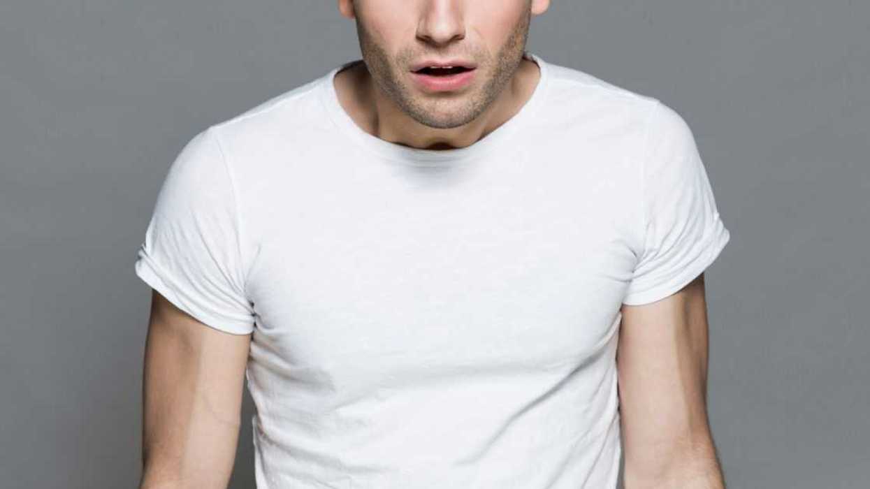 Studio shot of a stunned young man against a grey backdrop.
