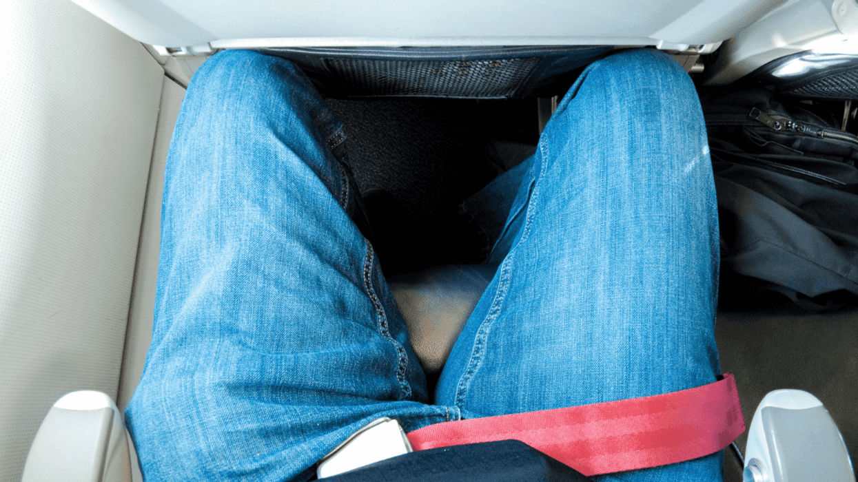 Tall man cramped in airplane seating