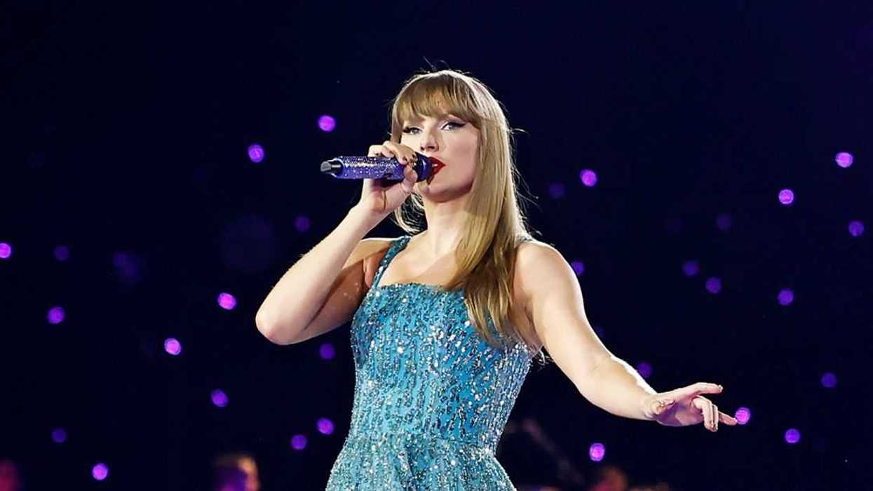 Taylor swift on stage in a blue dress with a microphone in her hand.