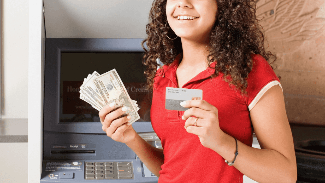 teen girl in front of ATM holding money and a debit card