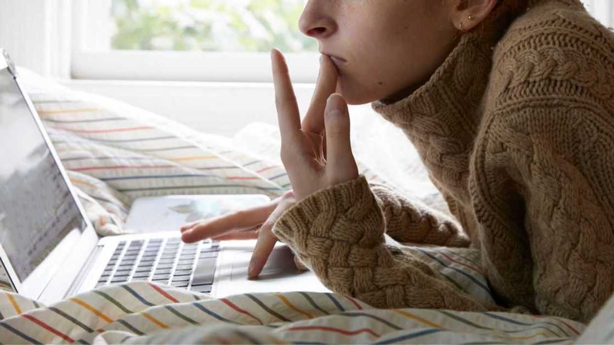 teen girl on laptop while laying on bed