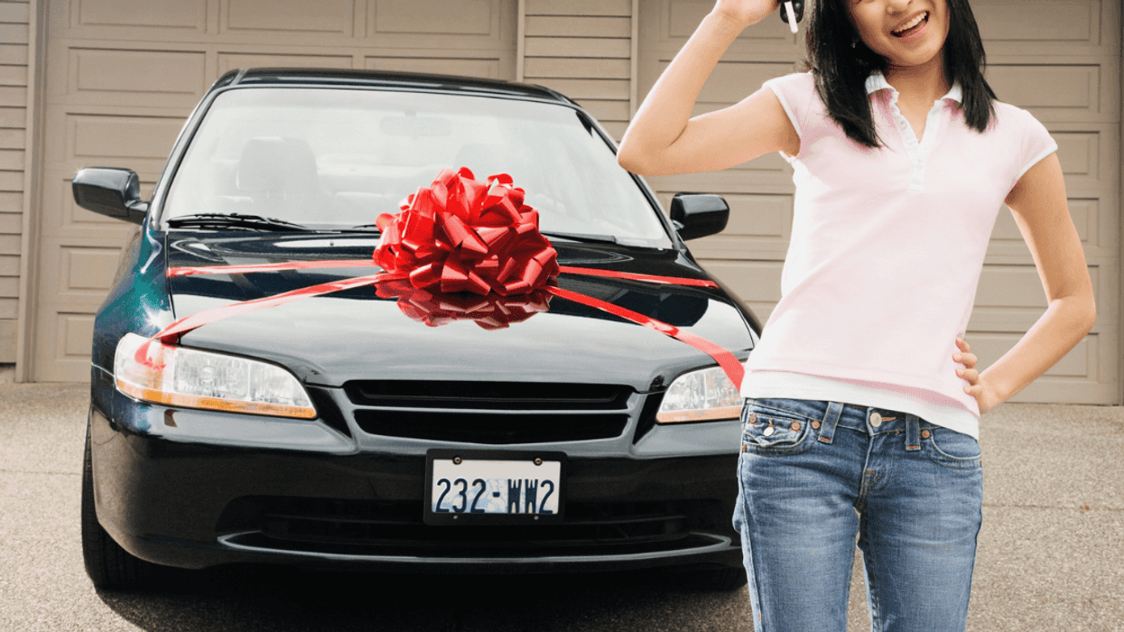 teen holding car keys in front of black car with red gift bow