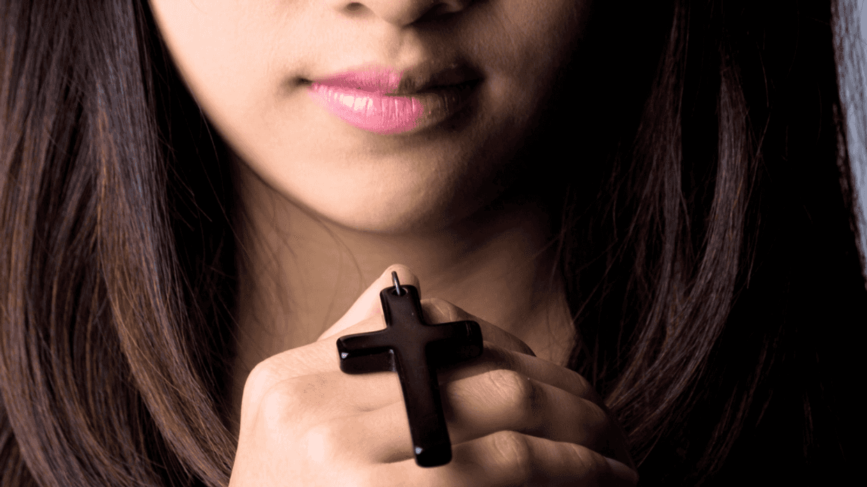 teen holds cross pendant in hand