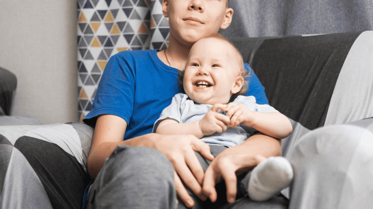 teenage boy holding a baby