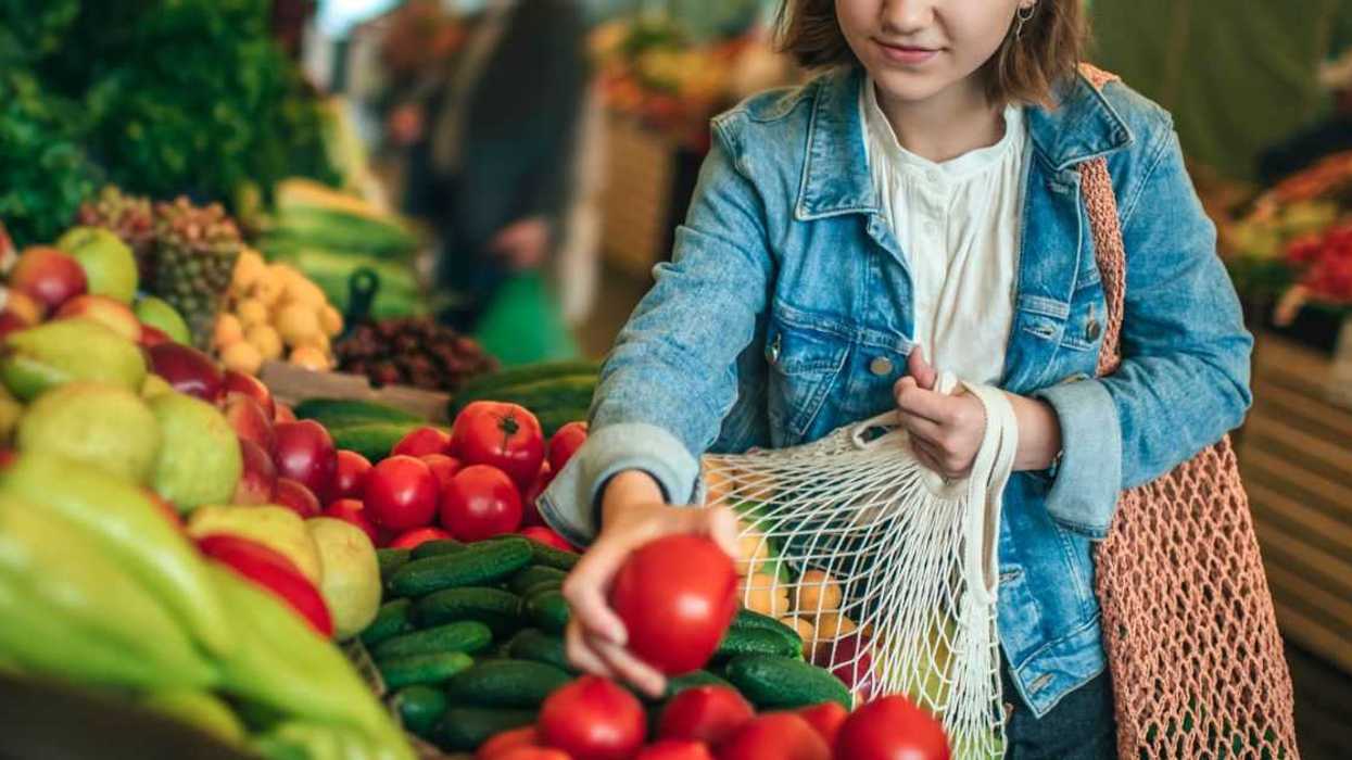 Teenager holding ecologically, friendly reusable bag with fruit and vegetables.