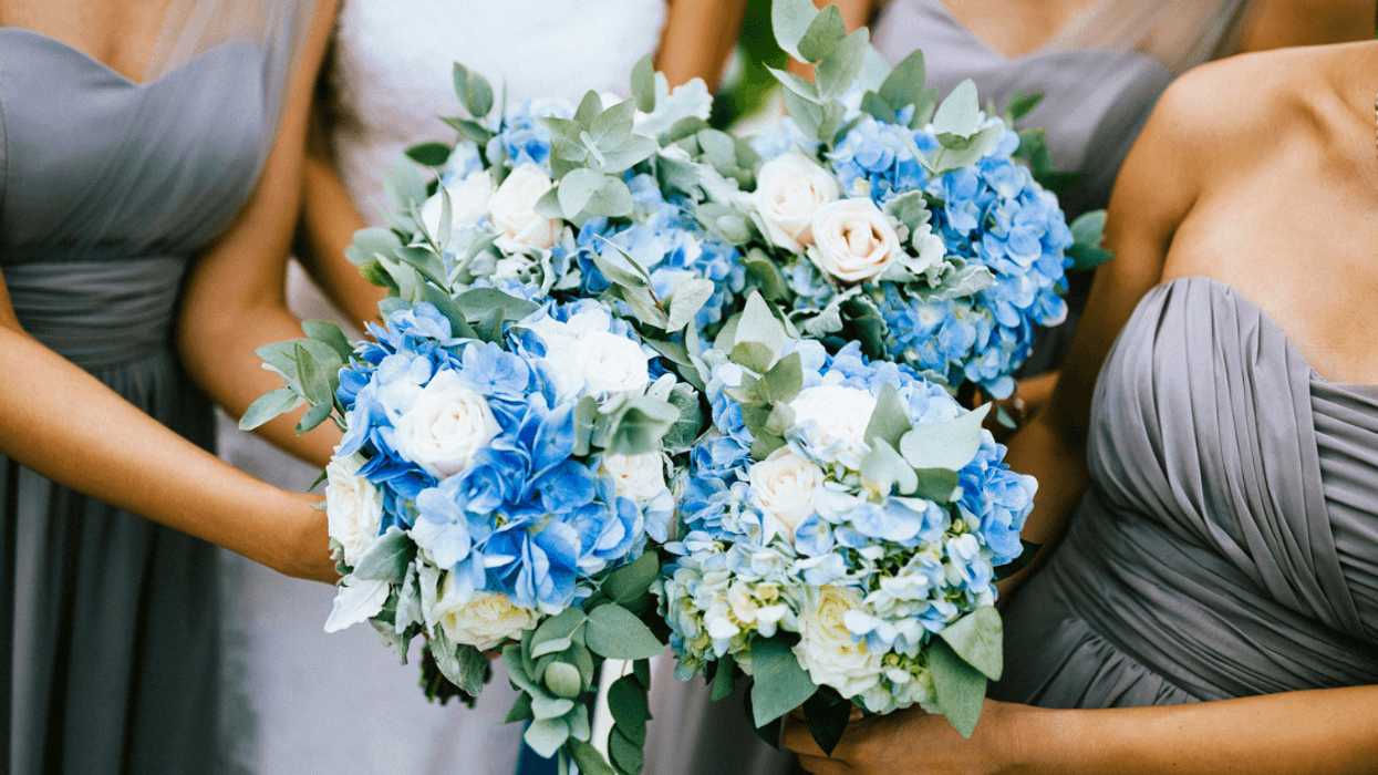 Three bridesmaids in gray, strapless bridesmaid's dresses surrounding a bride holding bouquets.