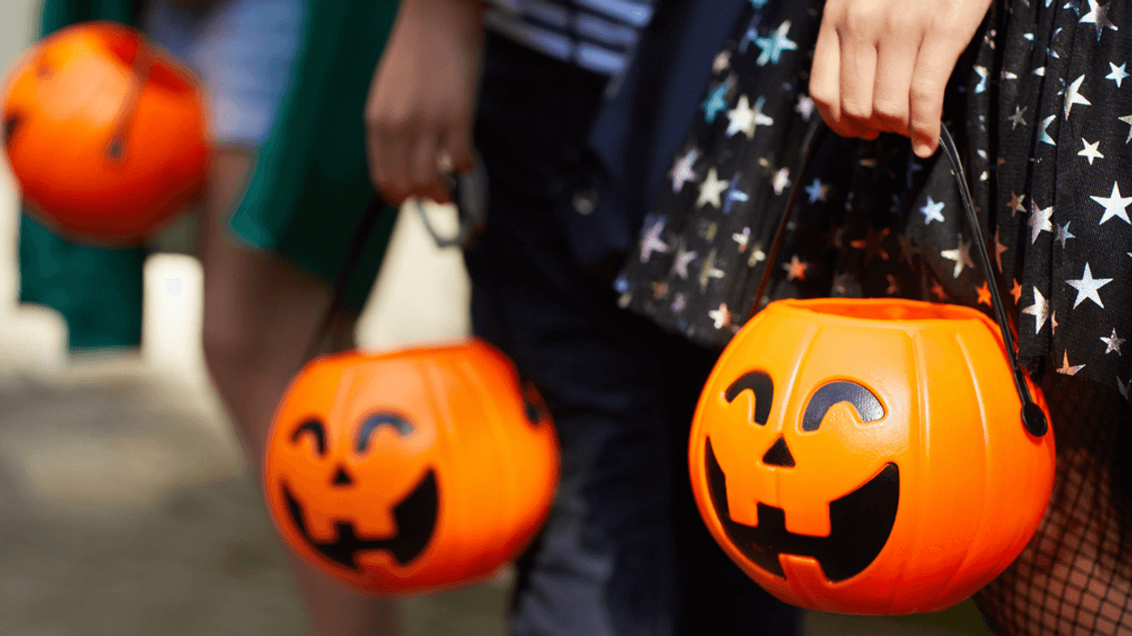 Three children holding pumpkin trick or treat buckets.