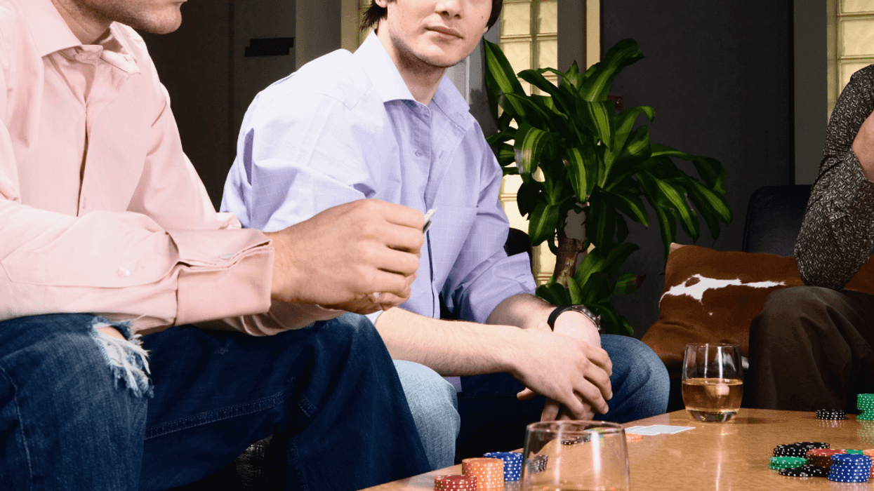 three men play poker in a living room of a home