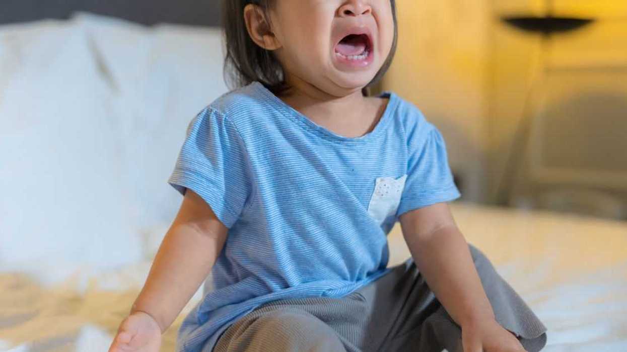 Toddler girl crying on the bed.