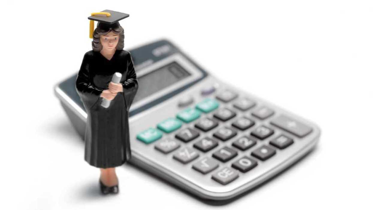 Toy figure of college graduate placed next to a calculator