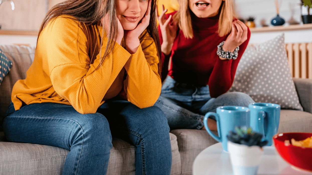 two adult women seated on couch arguing