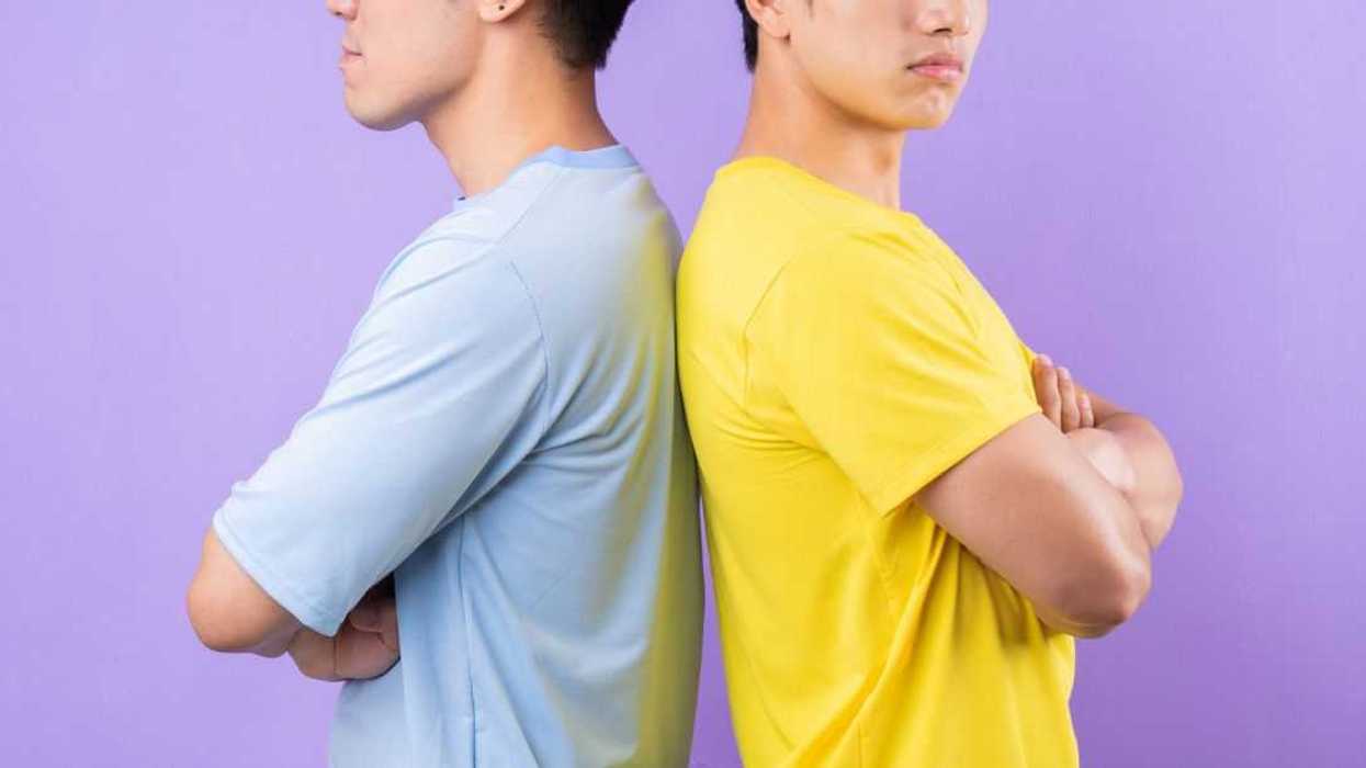 Two bothers standing back to back with their arms folded, they seem irritated. They stand against a lavender backdrop.