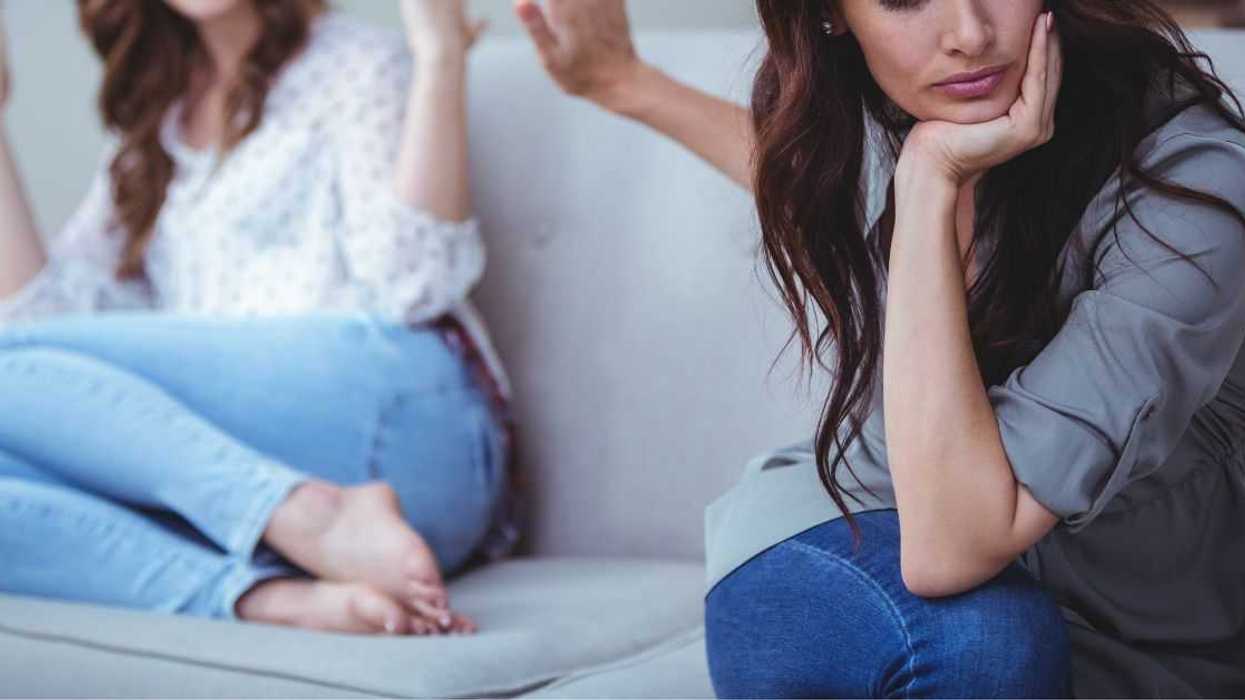 Two female friends sitting on sofa and arguing with each other