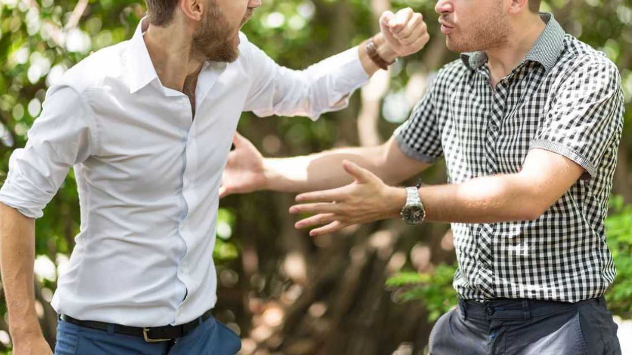 Two handsome and young furious men fighting with each other in the garden.