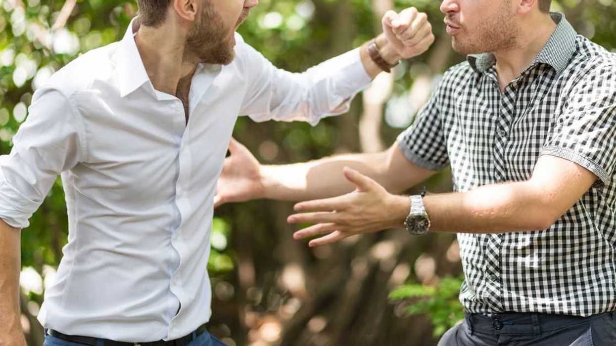 Two handsome and young furious men fighting with each other in the garden.