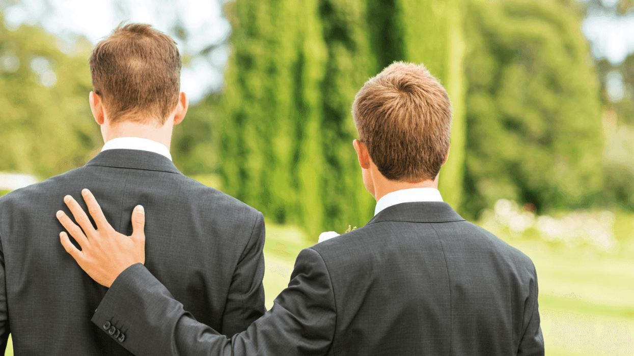 Two men in suits, with one resting his hand on the other's shoulder.