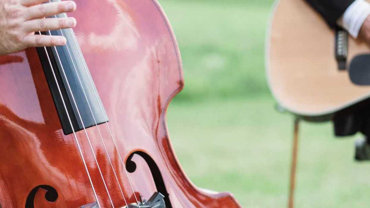 Two musicians playing stand up bass and guitar at wedding ceremony.