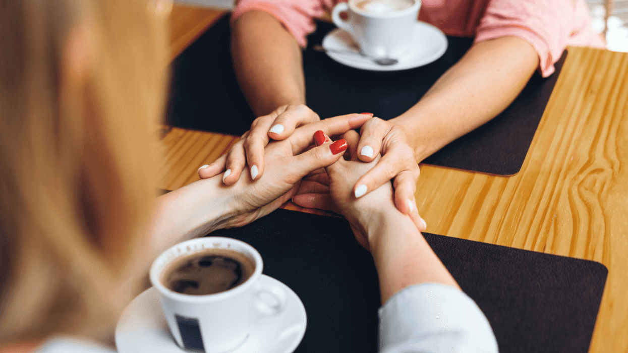 Two people holding hands across a restaurant table.
