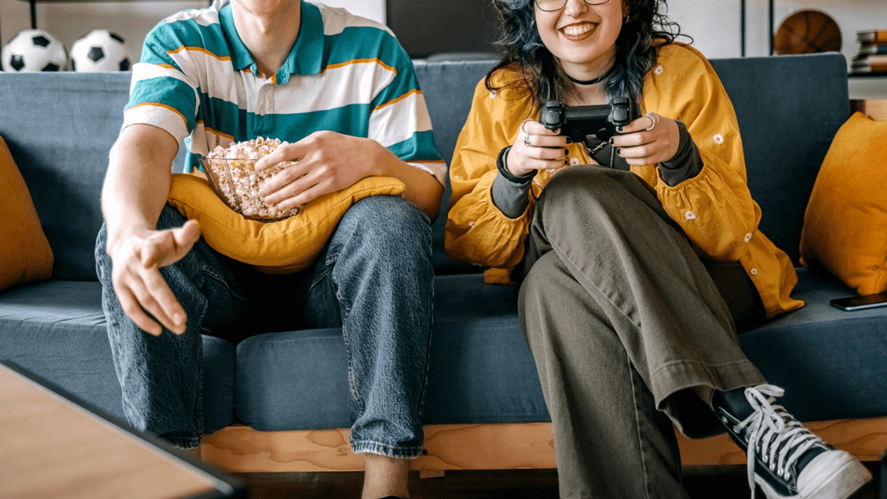 two people seated on couch playing video games