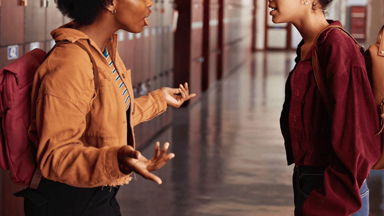 Two teenage girls in a school hallway having an argument.