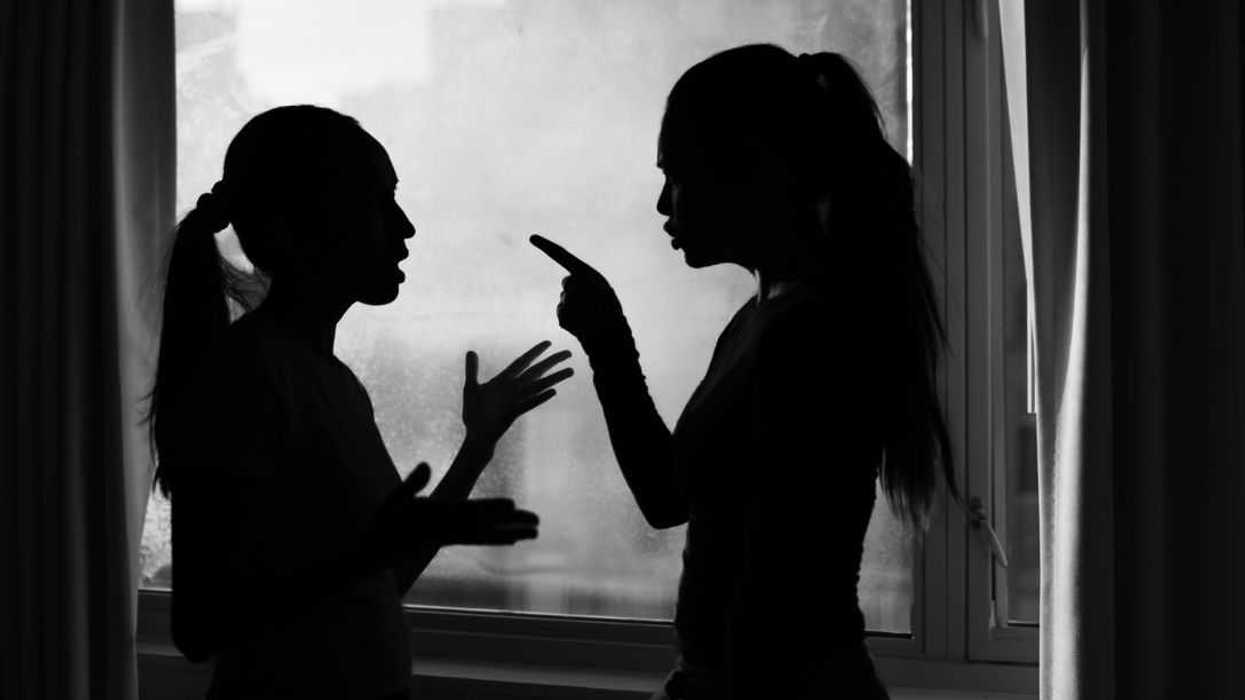 Two women argue in a silhouette. The photo is black and white.