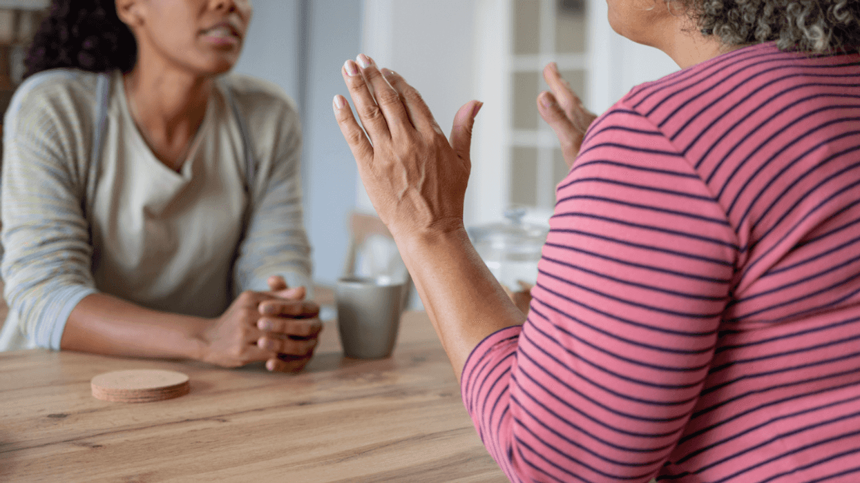 Two women having a discussion across a table from one another.
