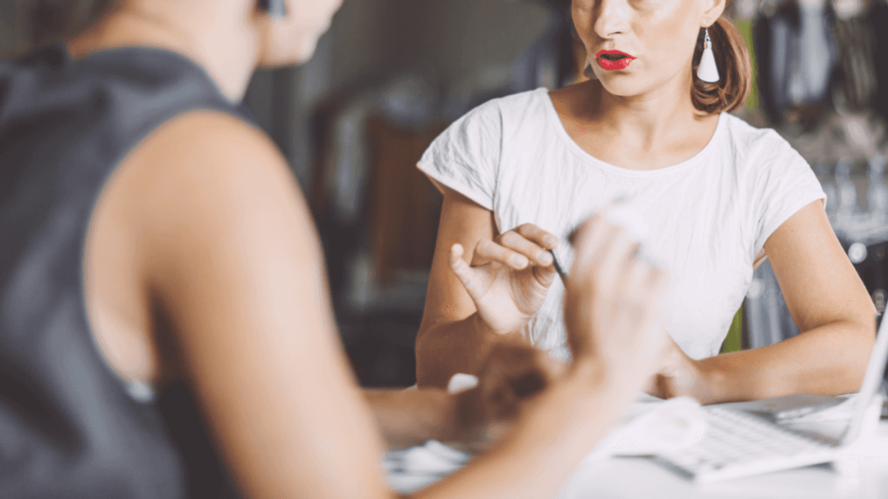 Two women sitting across from one another at a table having a tense conversation.