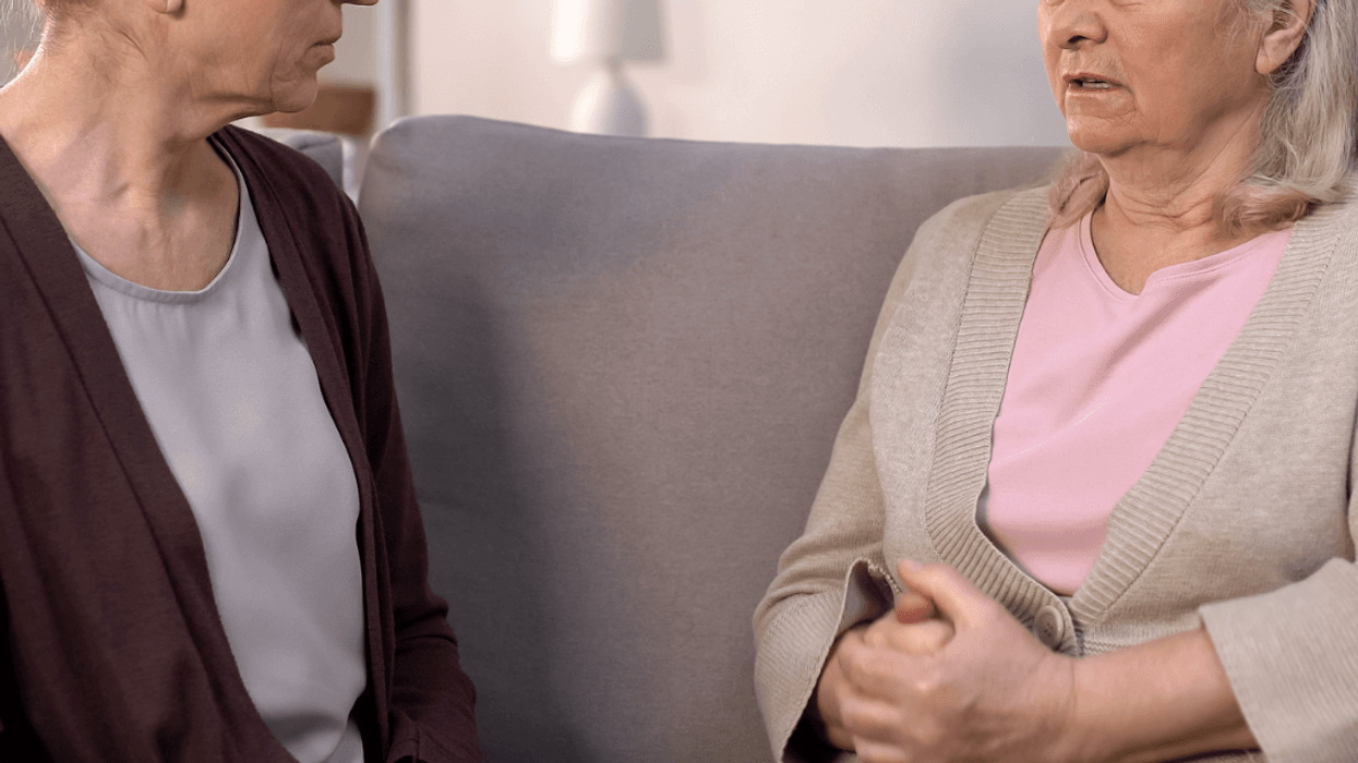 Two women sitting on the sofa having a serious conversation.