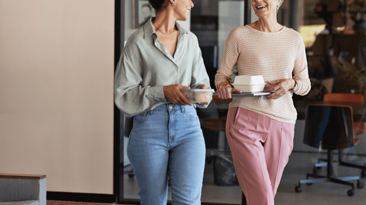 Two women walking and holding coffee cups.