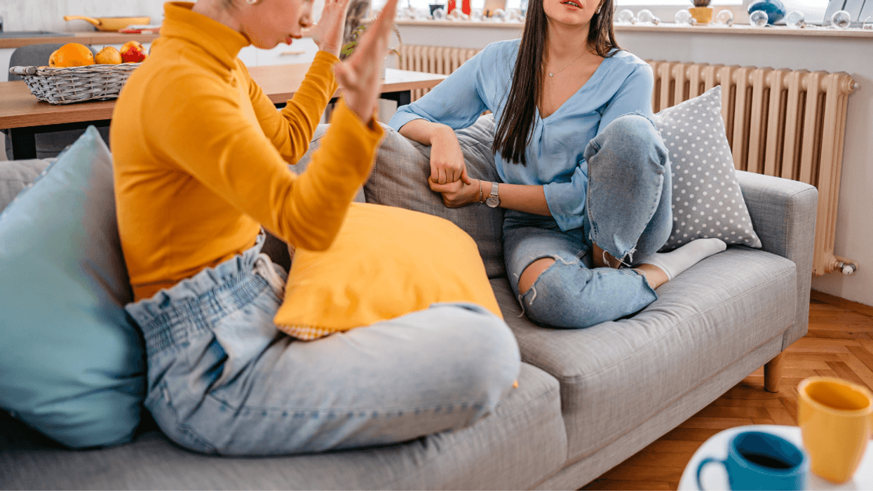 two young women seated on a couch arguing