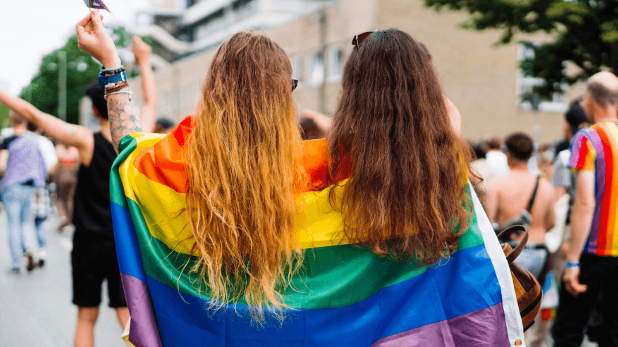 Two young women wrapped in a pride flag.