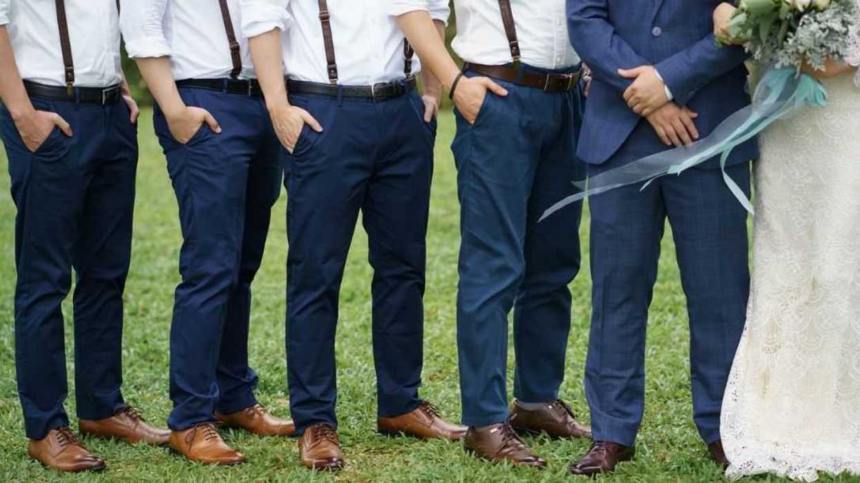 Unidentifiable groomsman pose beside a couple. The groomsmen are all wearing matching attire. Garden wedding. Concept wedding photo session.