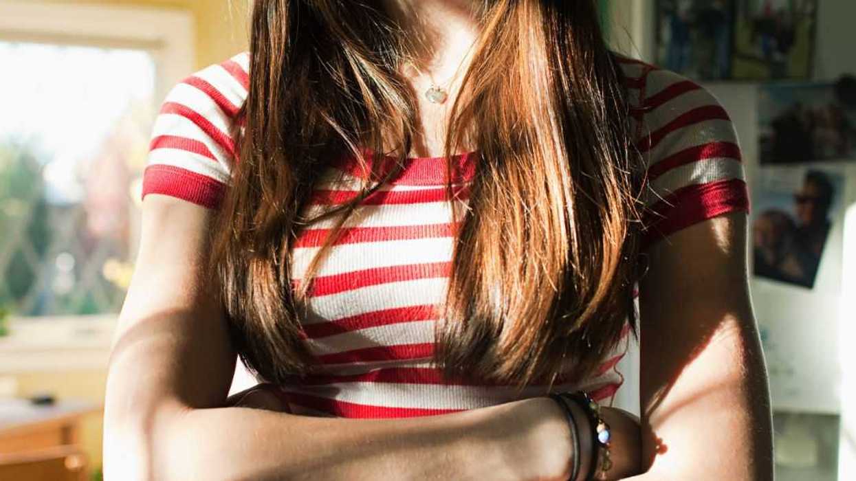 Unidentifiable teenage girl with arms crossed.