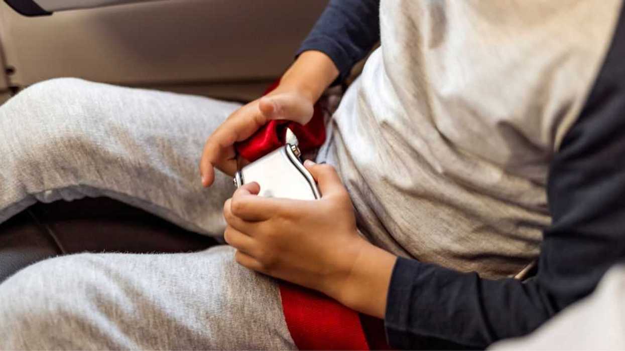 Unrecognizable child is fastening or unfastening their seat belt