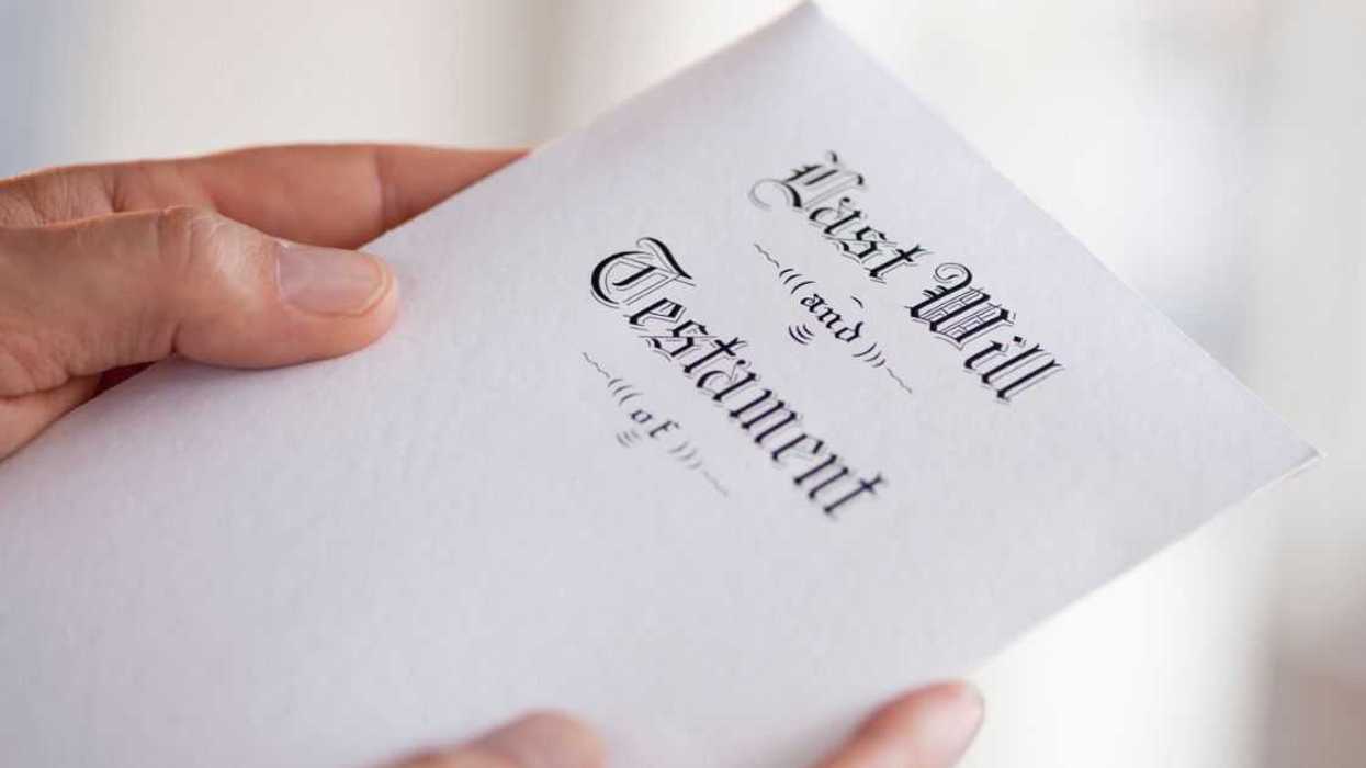 Up close shot of a man's hand holding a last will and testament.