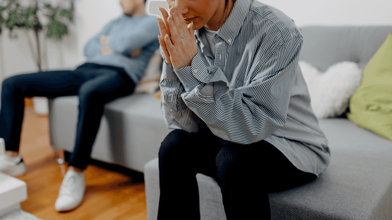 upset man and woman seated far apart on sectional couch