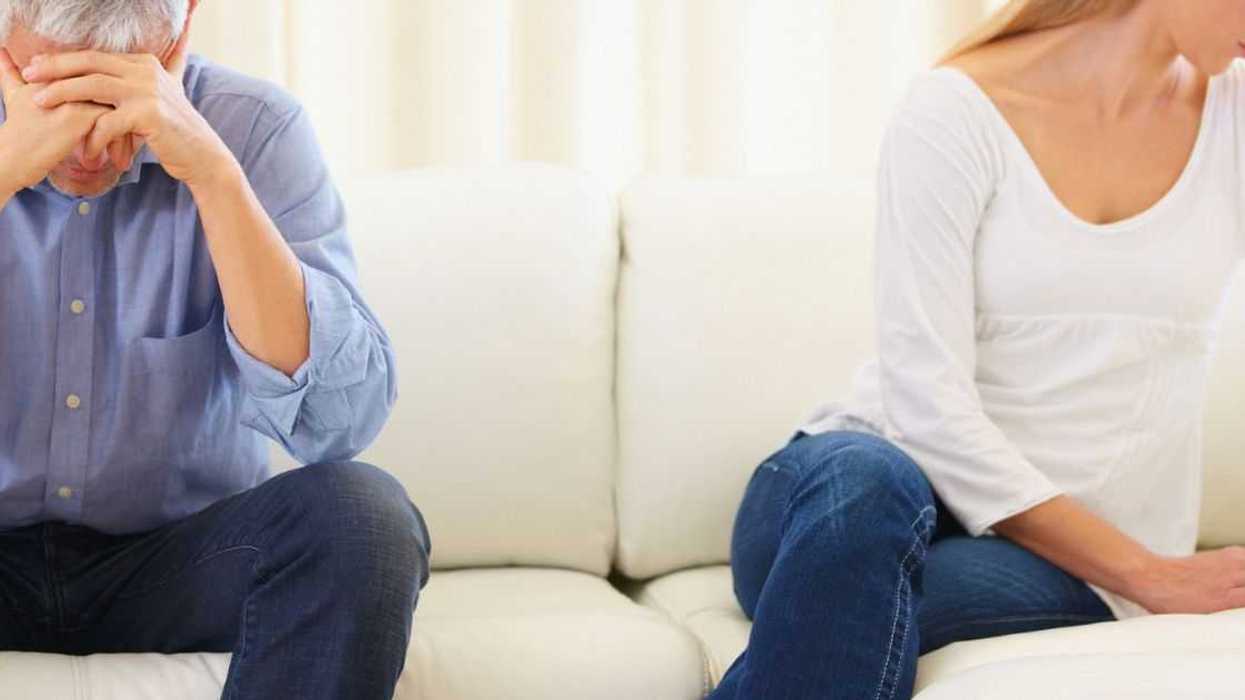 Upset married couple sitting on the sofa after a disagreement.