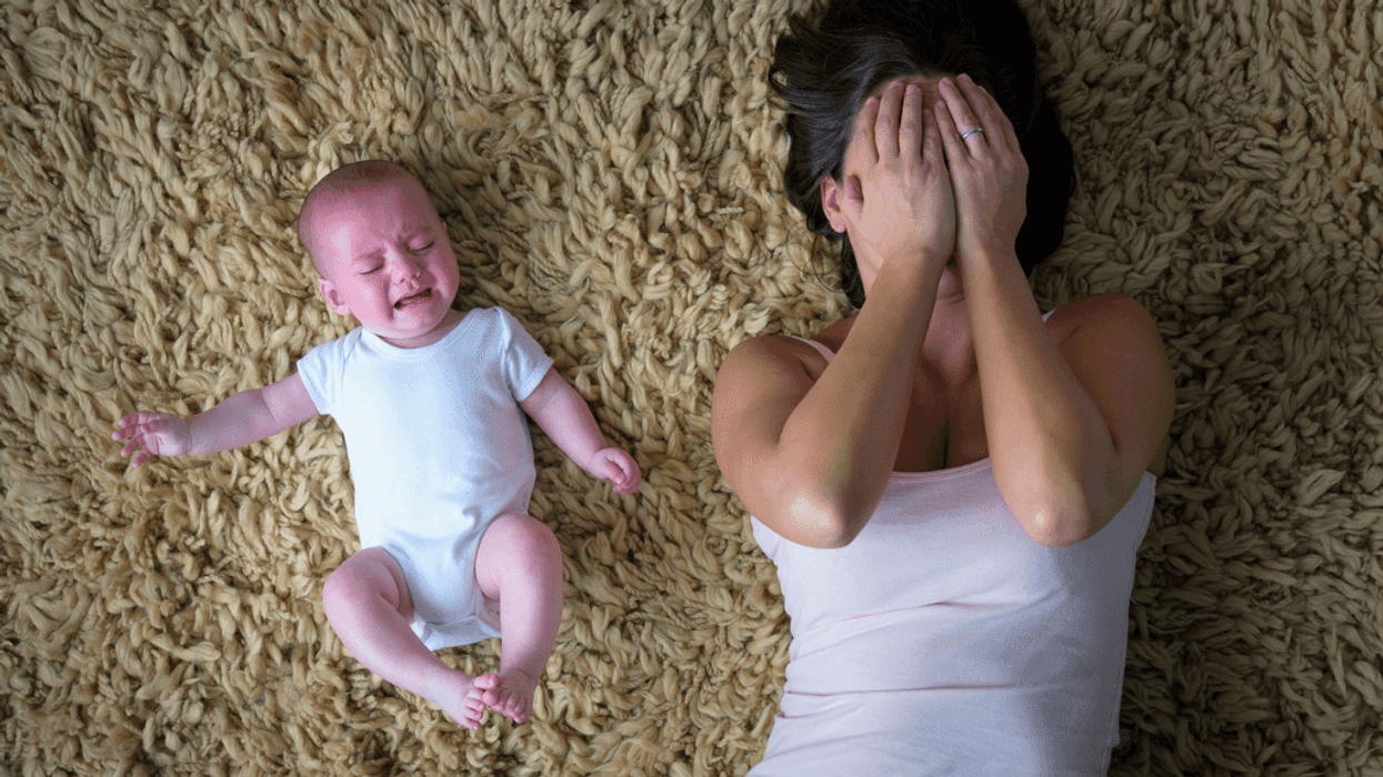 upset mother laying on floor next to crying infant