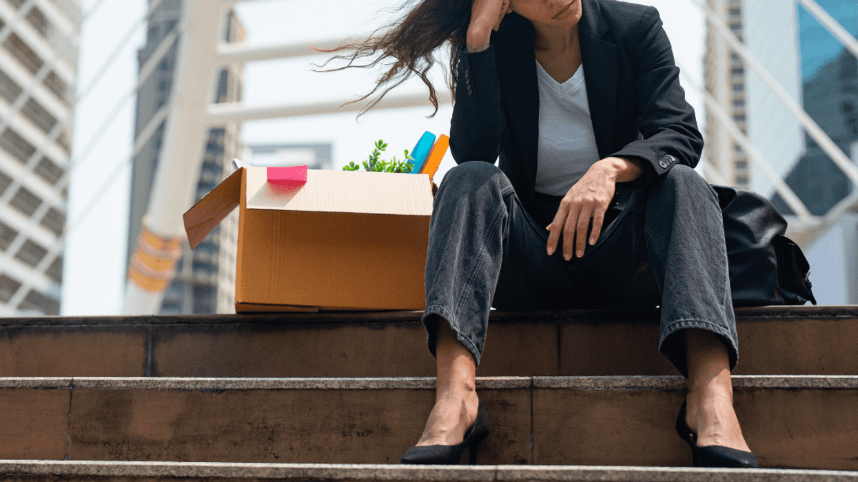 upset person sitting on steps with cardboard box of office belongings