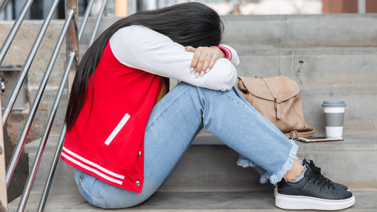 upset teen seated on high school steps
