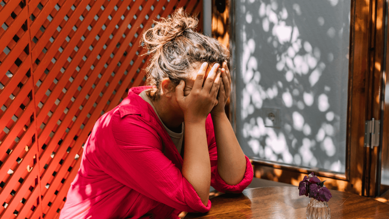 upset woman seated at table with her head in her hands