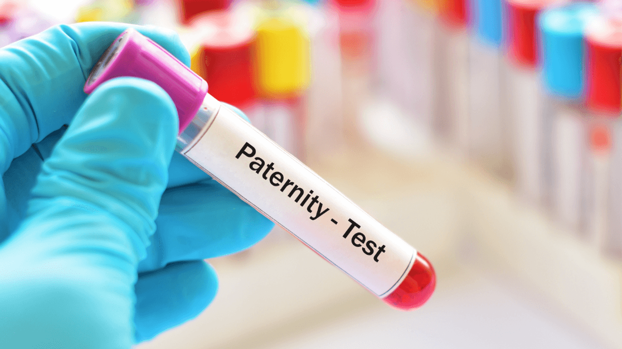 vial marked paternity test held by hand in blue glove