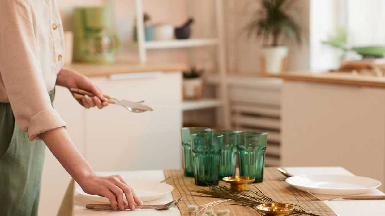 Warm toned side view portrait of young woman serving table in minimal kitchen interior.
