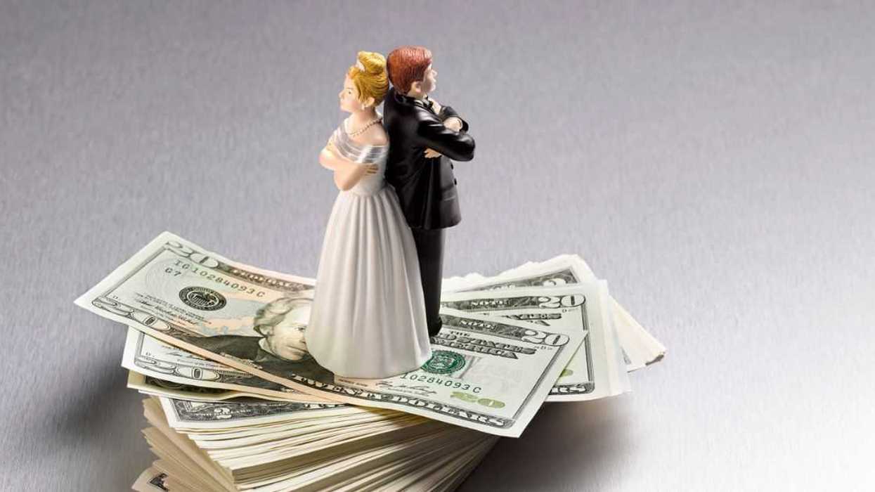 Wedding figurine couple back to back on a pile of Dollars.