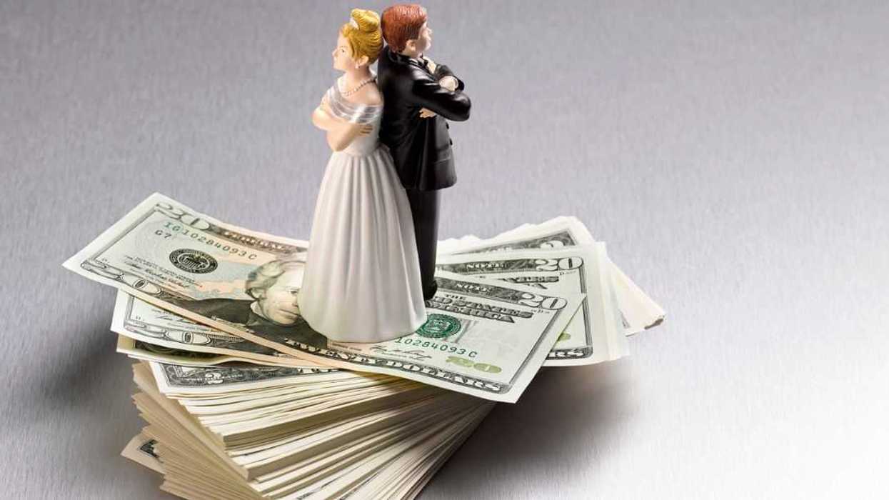 Wedding figurine couple back to back on a pile of dollars.
