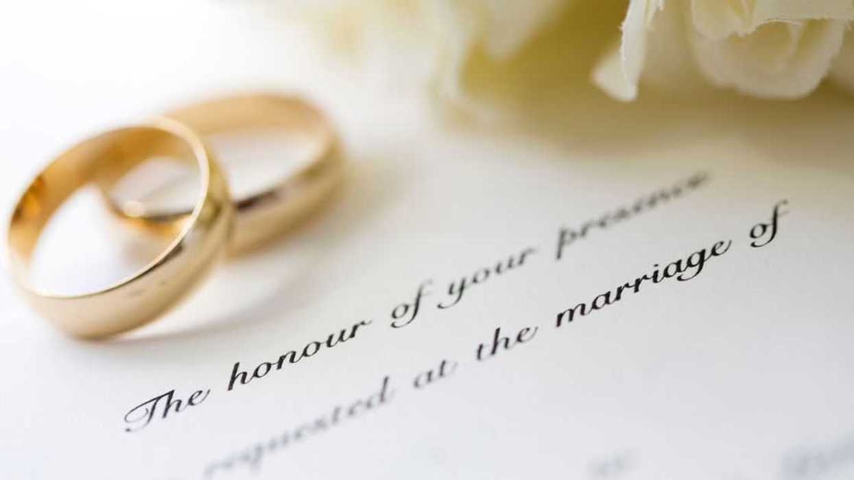 Wedding invitation with rings and a white rose bridal bouquet.