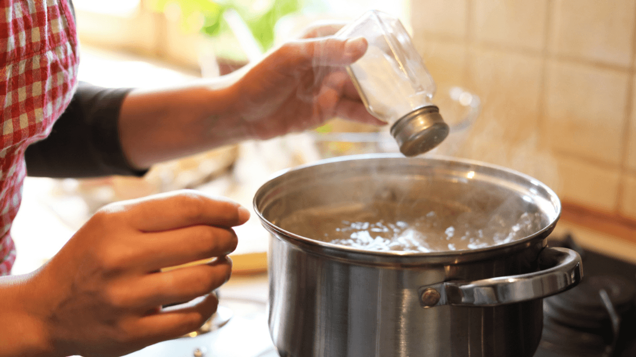 woman adding salt to pot on stove