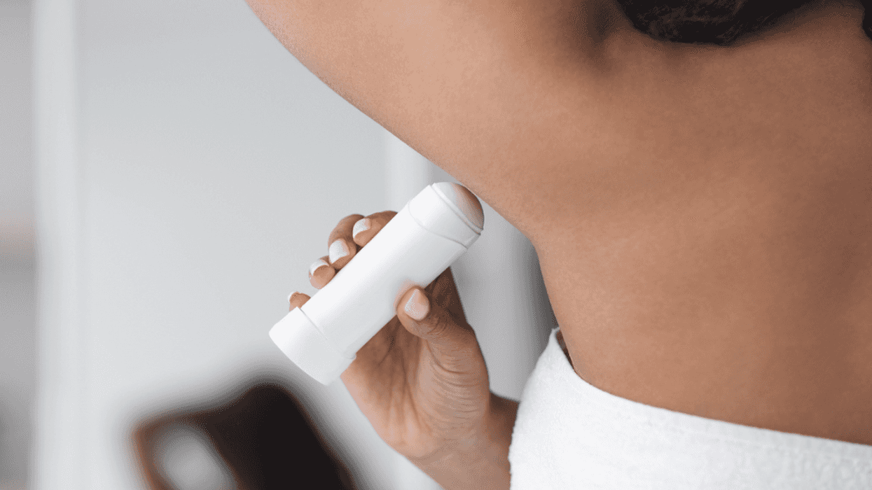woman applying deodorant to her armpit