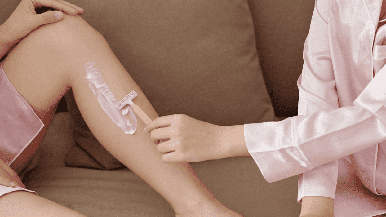 Woman assisting another woman in shaving her legs